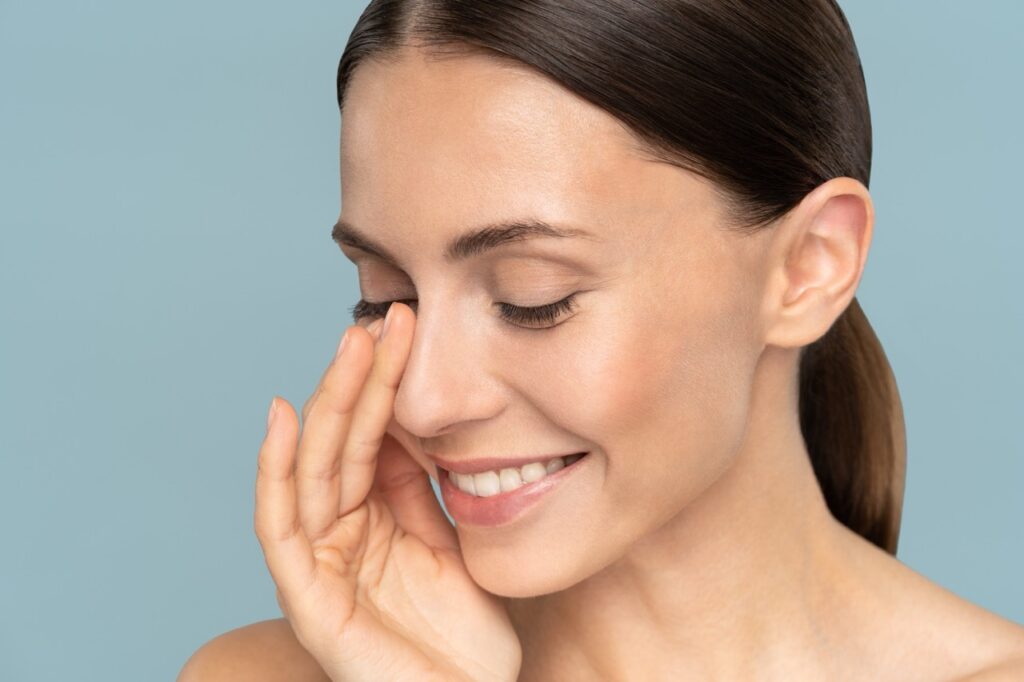 smiling-woman-with-healthy-skin-touches-her-face-2026-03-19-22-08-31-utc Large