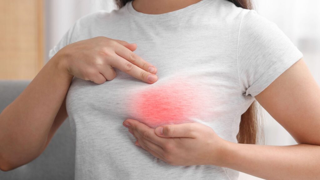 Woman holding her hand over a sore area of her breast